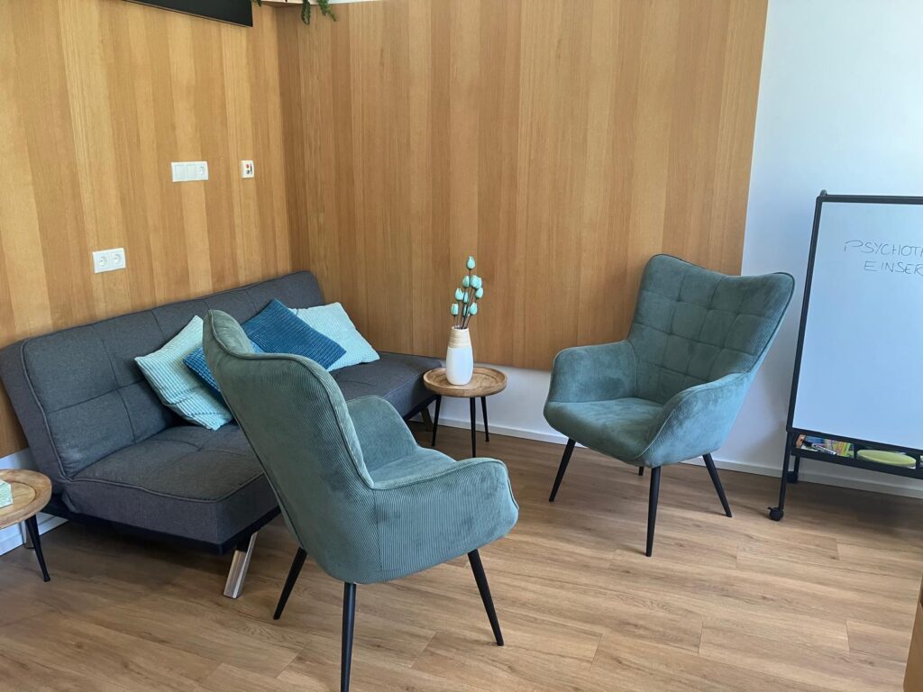 Psychotherapiepraxis - zwei grüne Sessel, Beistelltisch und Couch im Hintergrund